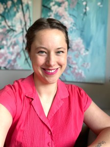 Carmen Wood a smiling white woman with a pink top and pink lipstick smiles at the camera